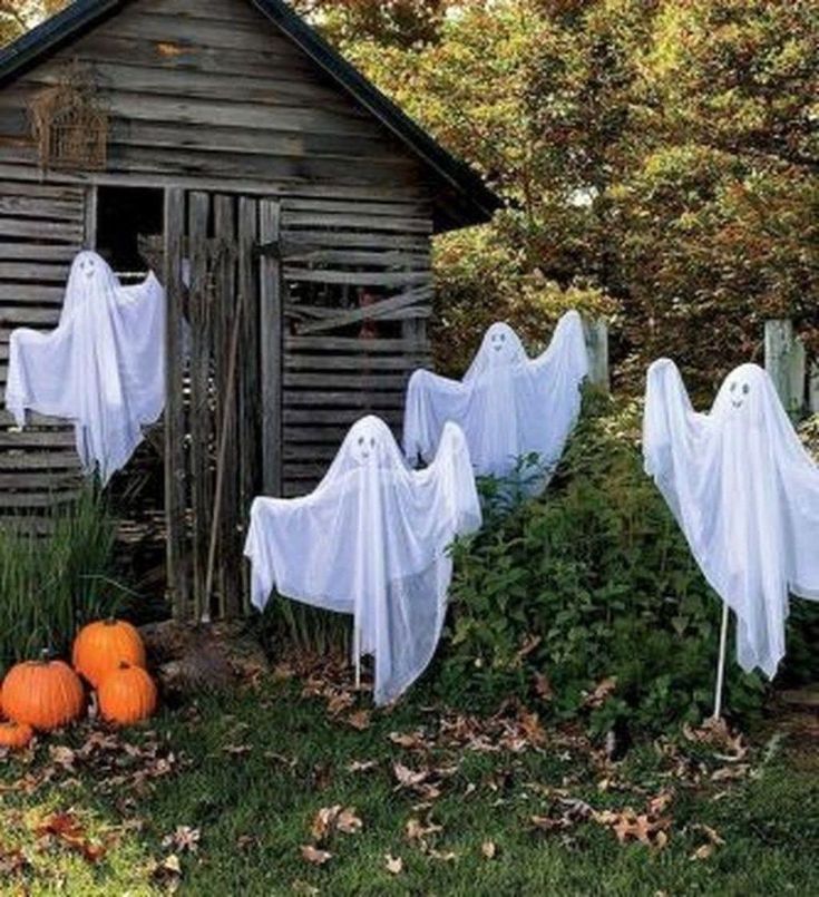 halloween decorations with ghost heads and pumpkins in front of an outhouse