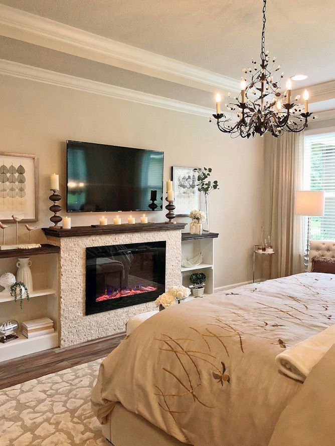 a bedroom with a bed, fireplace and chandelier in the middle of it