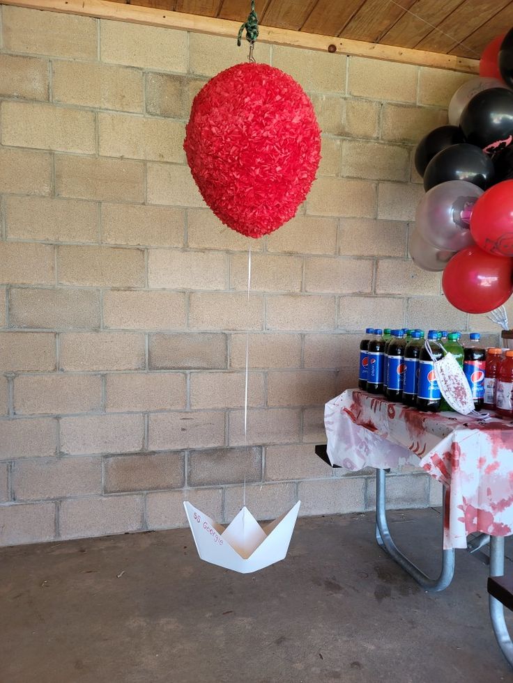 a party with balloons, sodas and paper boats hanging from the ceiling in front of a brick wall