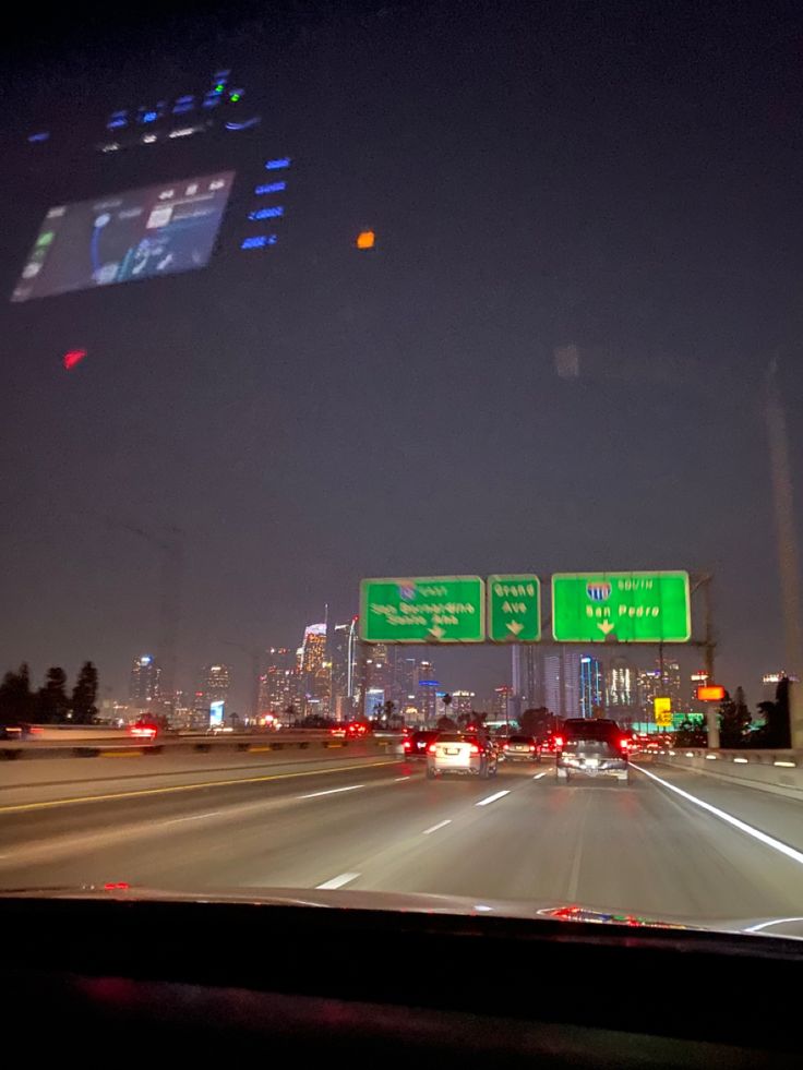 cars driving down the highway at night with city lights in the background