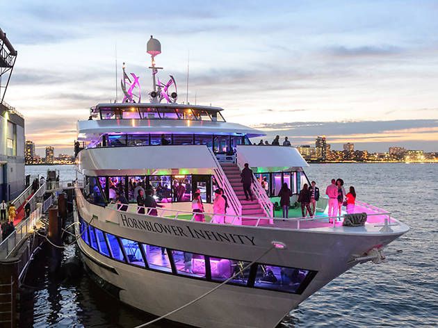 a large white boat with people standing on it's deck in the water at dusk