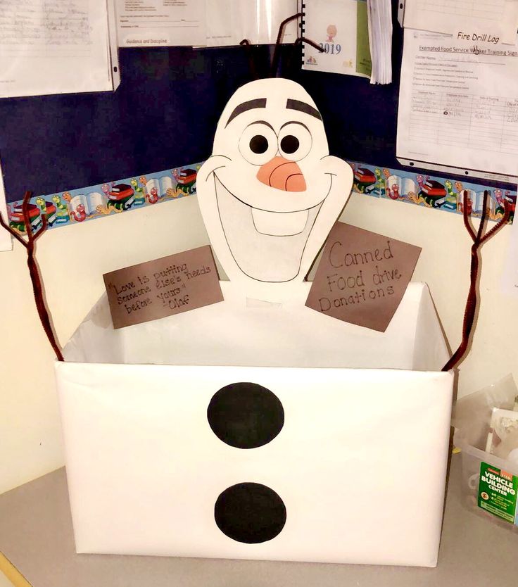 a cardboard box with a snowman face on it and some notes attached to the lid