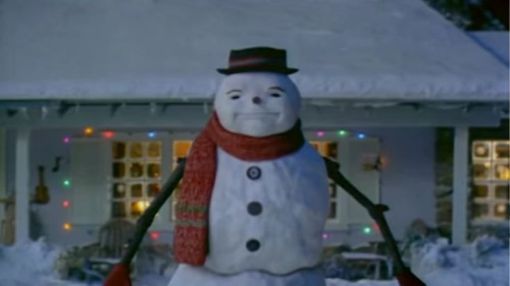 a snowman is standing in front of a house