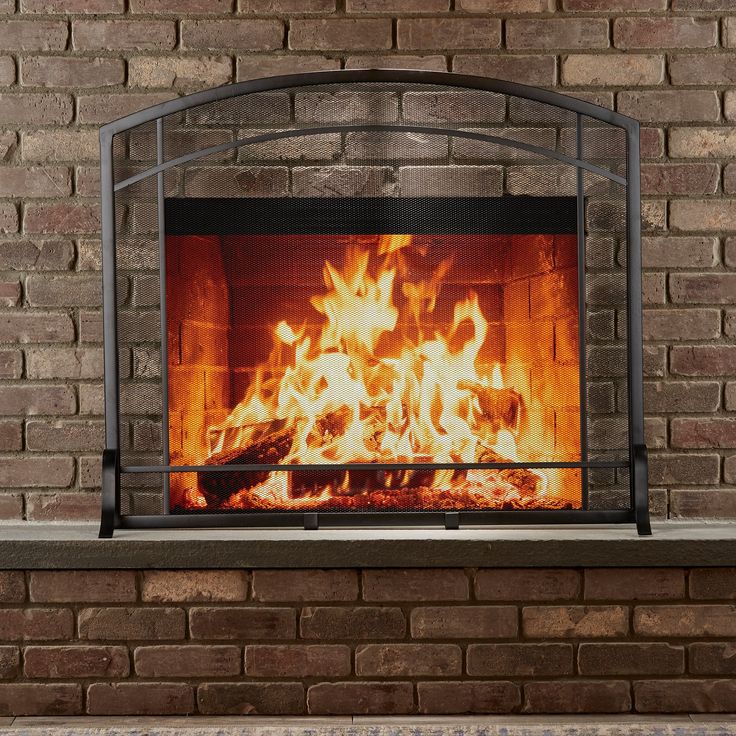 a fire burning in a brick fireplace next to a stone wall with an iron frame