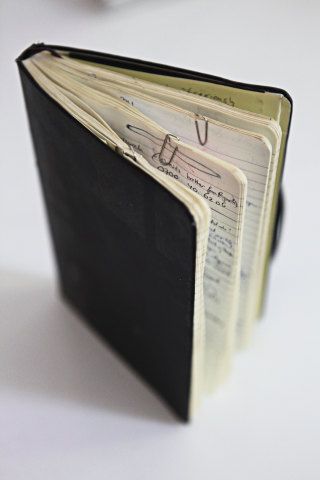 an open book with writing on it sitting on a table next to a computer keyboard