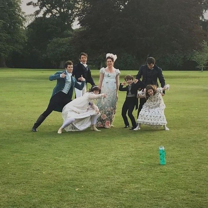 a group of people standing on top of a lush green field next to each other