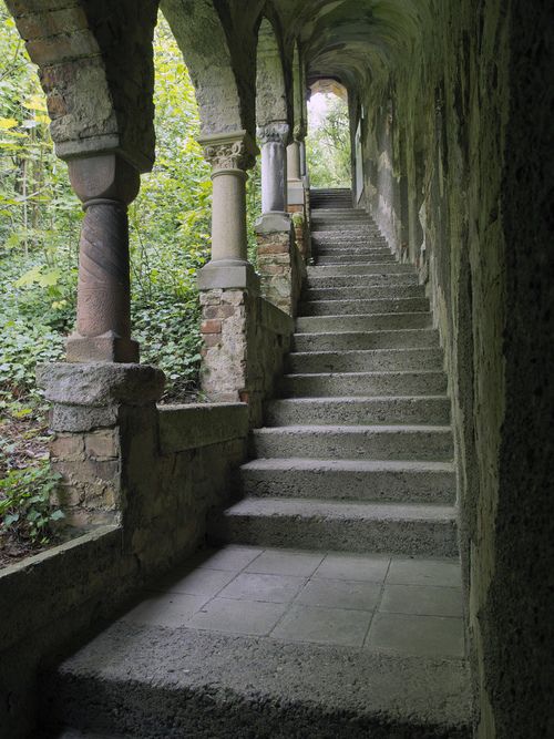 some stone steps leading up to an archway in a building with columns and arches on both sides