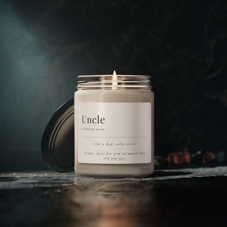 a candle sitting on top of a wooden table next to a black wall with the word unclee printed on it