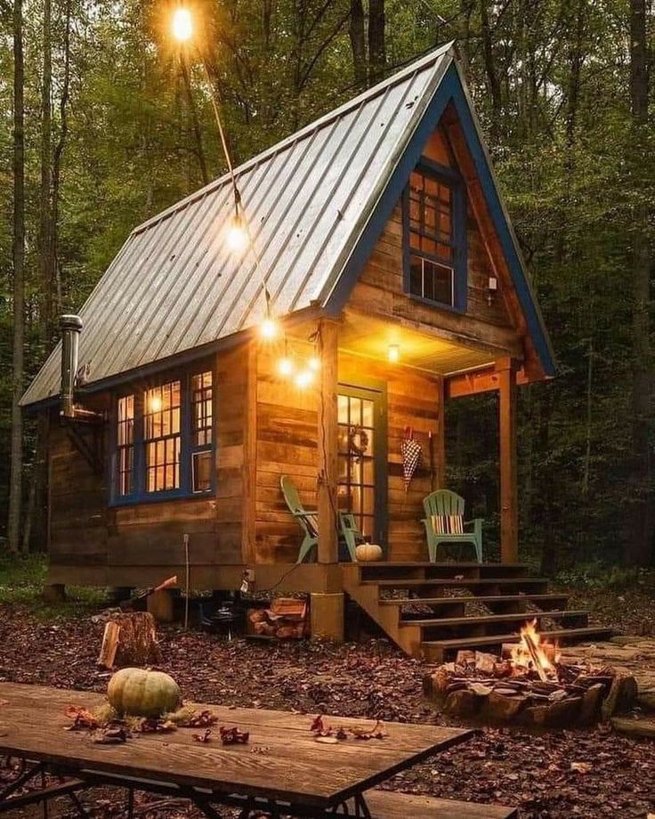 a small cabin in the woods is lit up with lights and wood chips on the ground