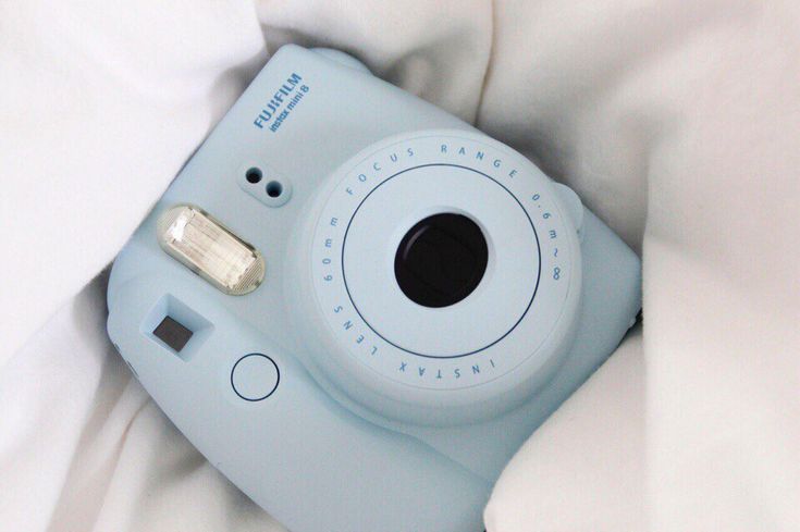 a camera is laying on top of a white bed sheet with the cover pulled down