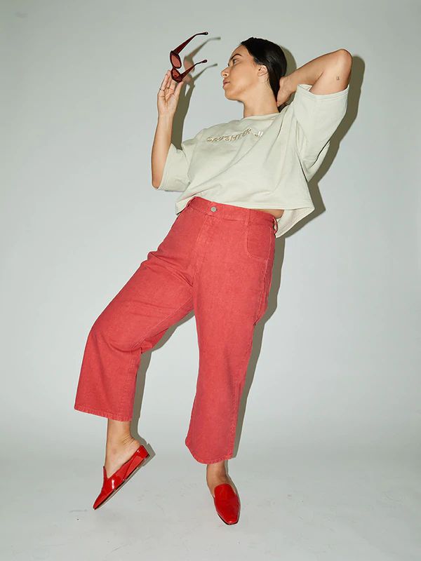 a woman in red pants holding scissors up to her face