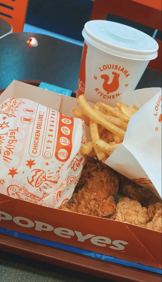 chicken and french fries in a box with a cup of coffee next to it on a table