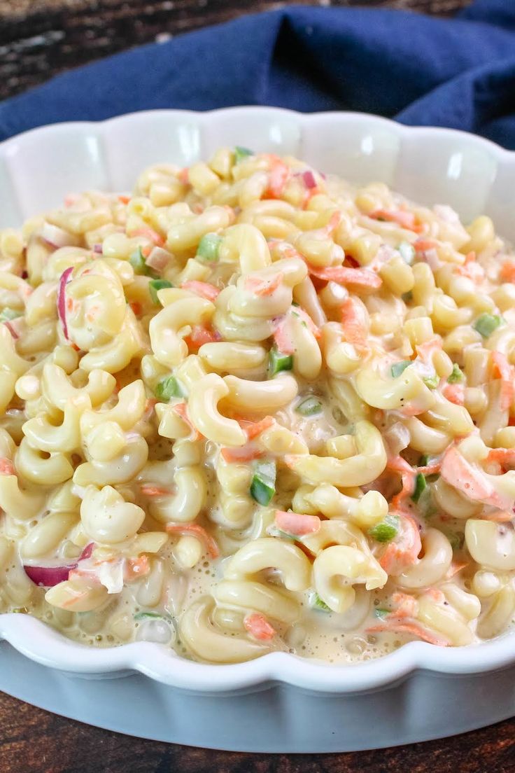 a white bowl filled with macaroni salad on top of a wooden table