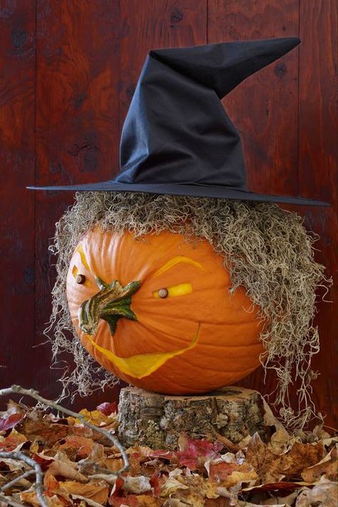 a pumpkin sitting on top of a pile of hay with a witches hat on it