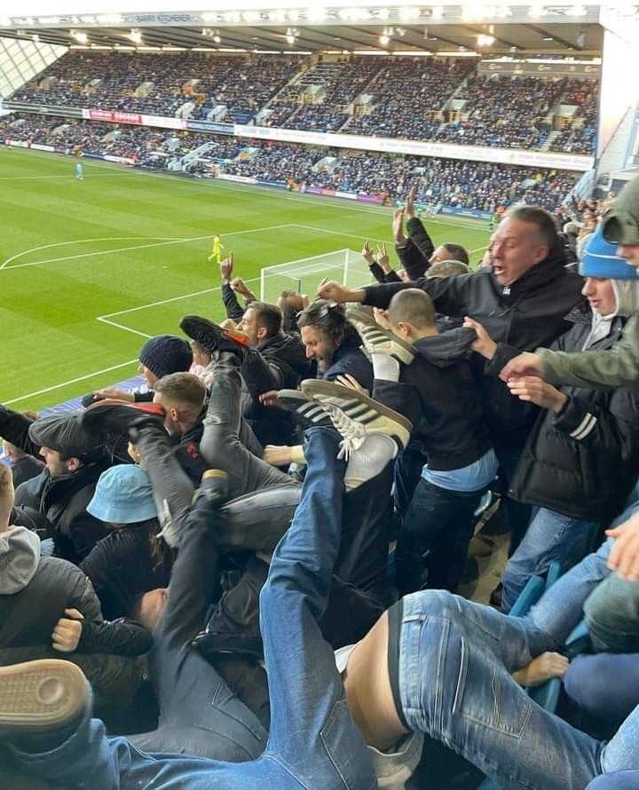 a group of people sitting on top of a soccer field with their hands in the air