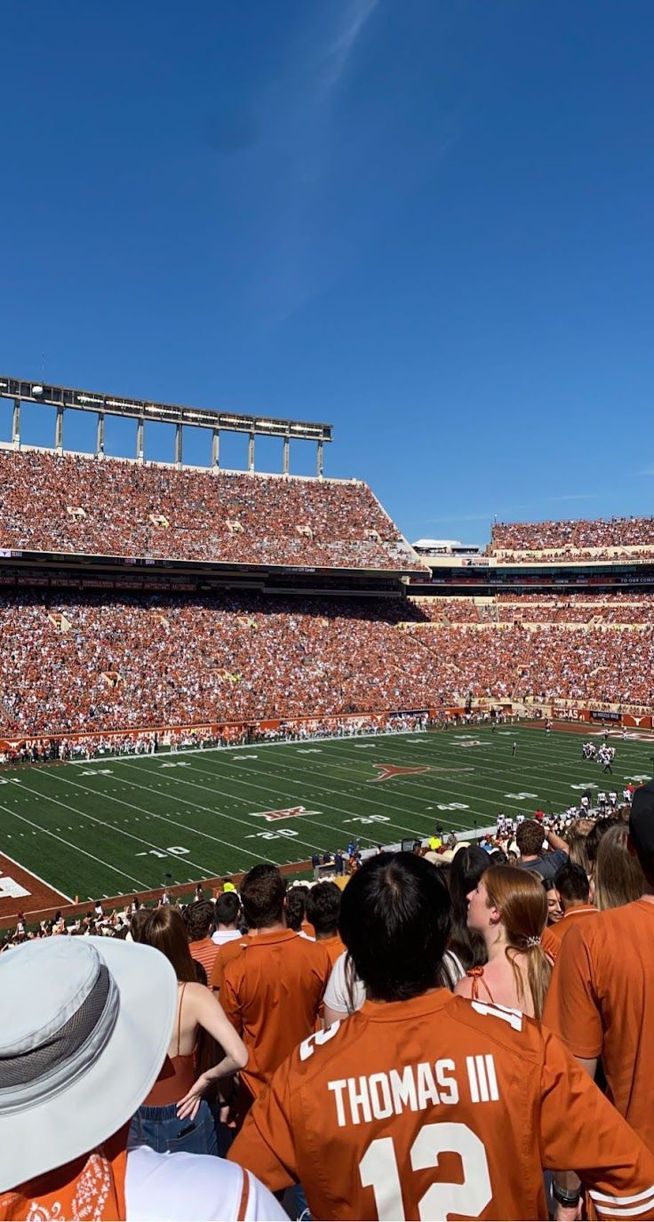 a football stadium filled with people watching the game on a sunny day in orange and white