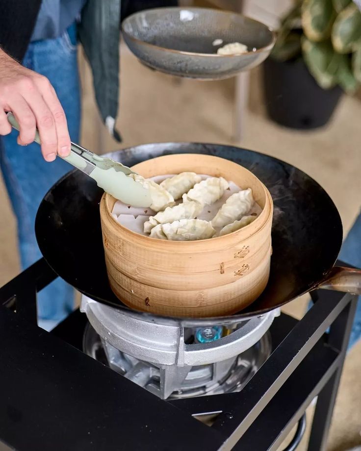 a person cooking food in a pot on top of an open stove burner with a spatula