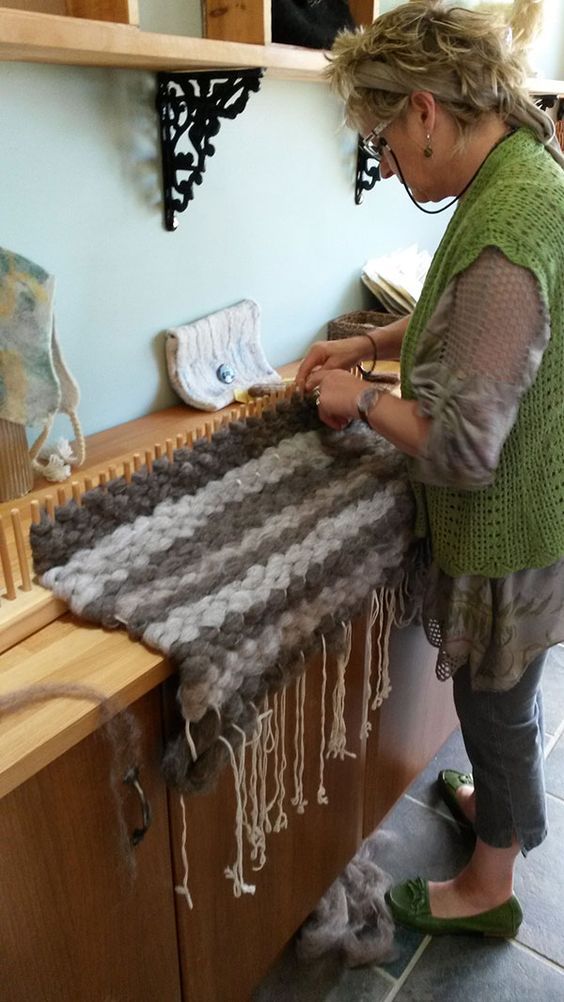 a woman standing in front of a table with a weaving machine on top of it