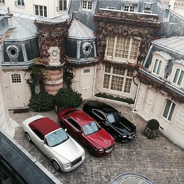 three cars are parked in front of a building with many windows and balconies