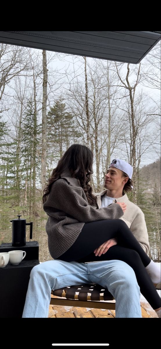 two people sitting on a picnic table in the woods, one with her legs crossed