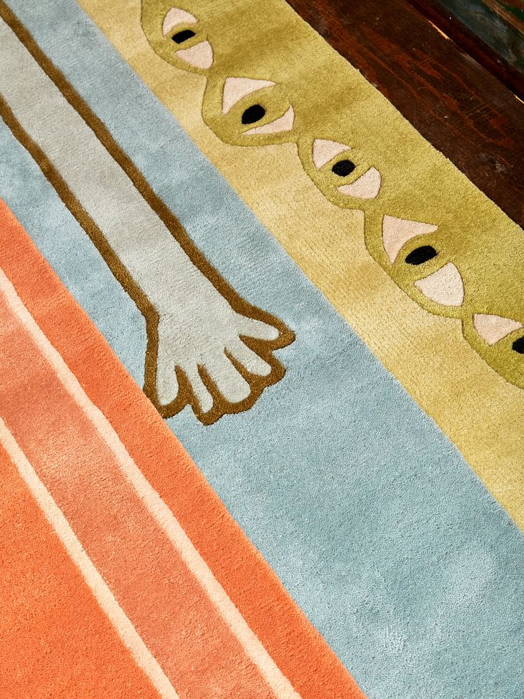 a colorful rug with an abstract design on the floor in front of a wooden table