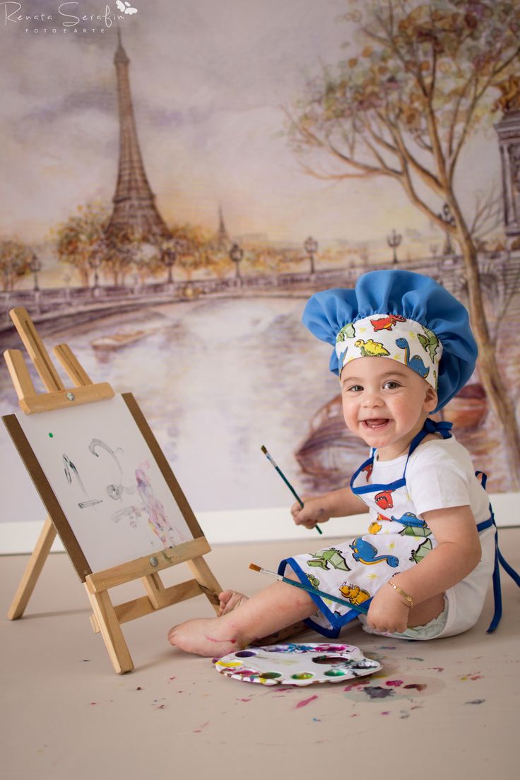 a baby sitting on the floor in front of an easel