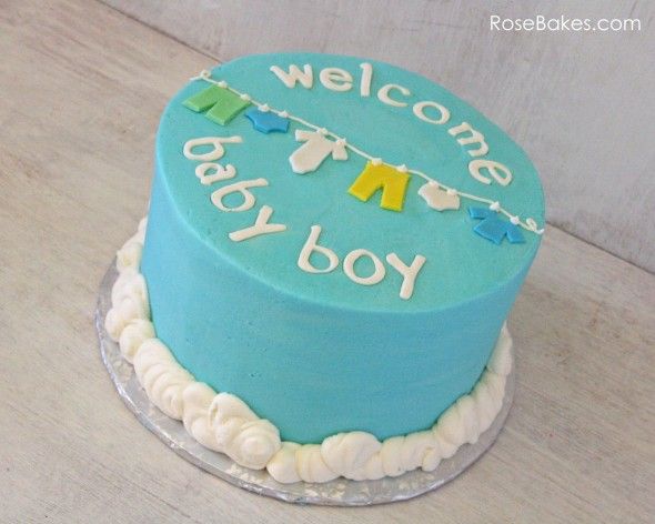 a welcome baby boy cake with blue frosting and bunting on the top, sitting on a table