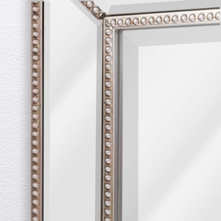 a mirror that is on the wall with beaded trimmings and silver frame