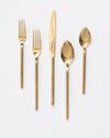 gold colored utensils and spoons are arranged in a row on a white surface