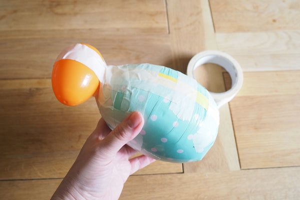 a hand holding an orange and white balloon