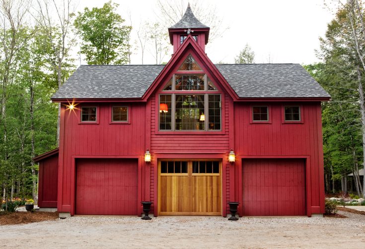 a large red barn with two garages on the front and one above it's doors