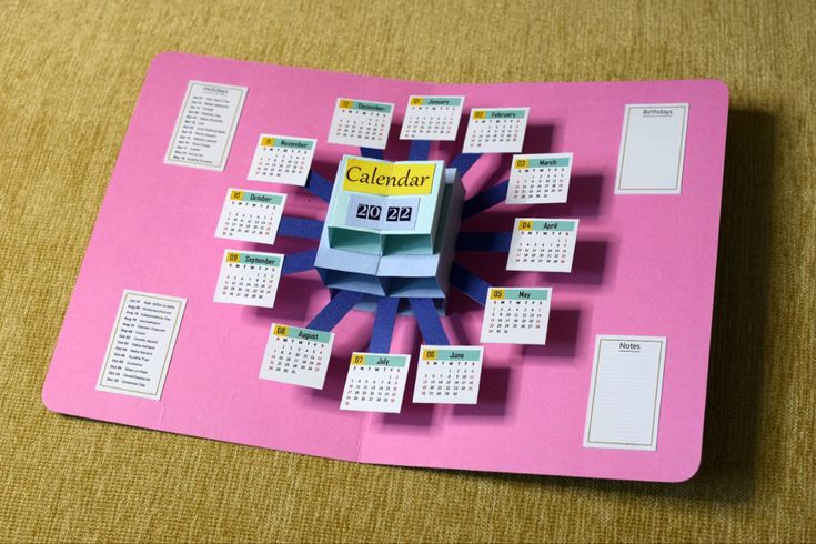 a paper calendar is displayed on a pink surface