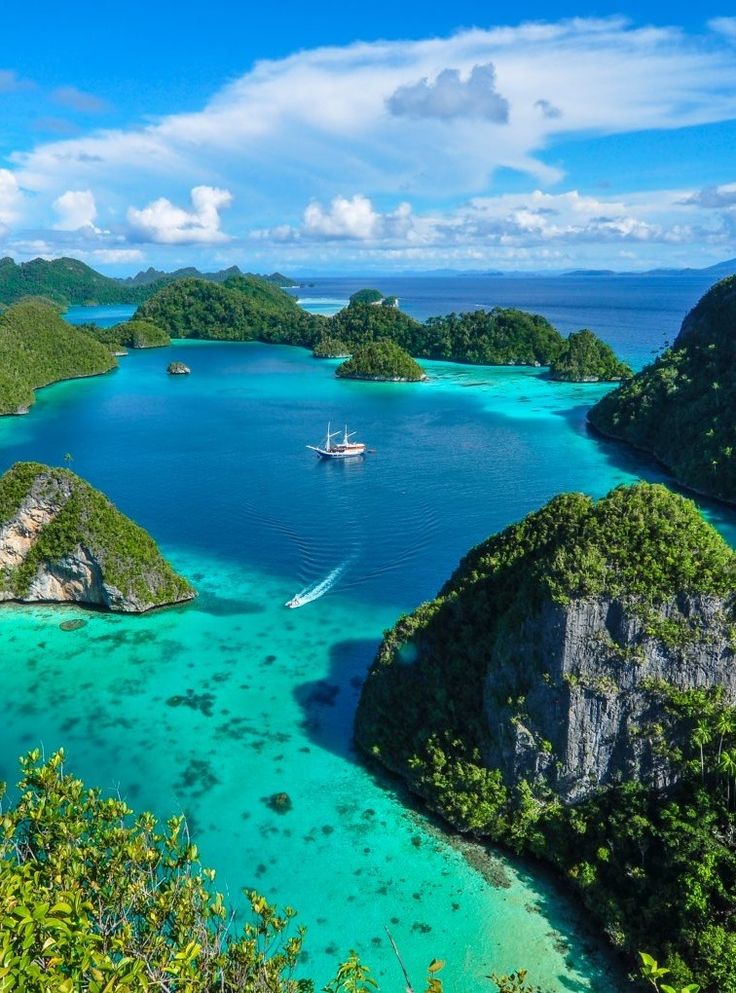 an aerial view of several small islands in the ocean with boats floating on them and surrounded by greenery