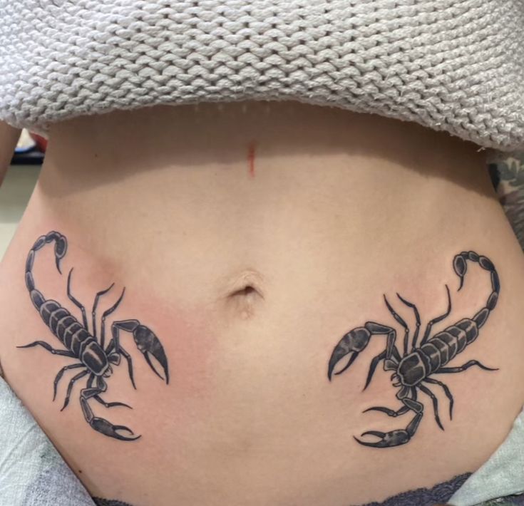 a woman's stomach with two scorpion tattoos on her side and the lower part of her belly