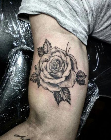 a black and white rose tattoo on the right arm, with leaves around it's edges