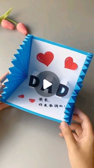 someone holding up a card with the word dad written on it and hearts in the background