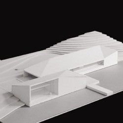 an architectural model of a house with white walls and windows on the roof, in front of a black background