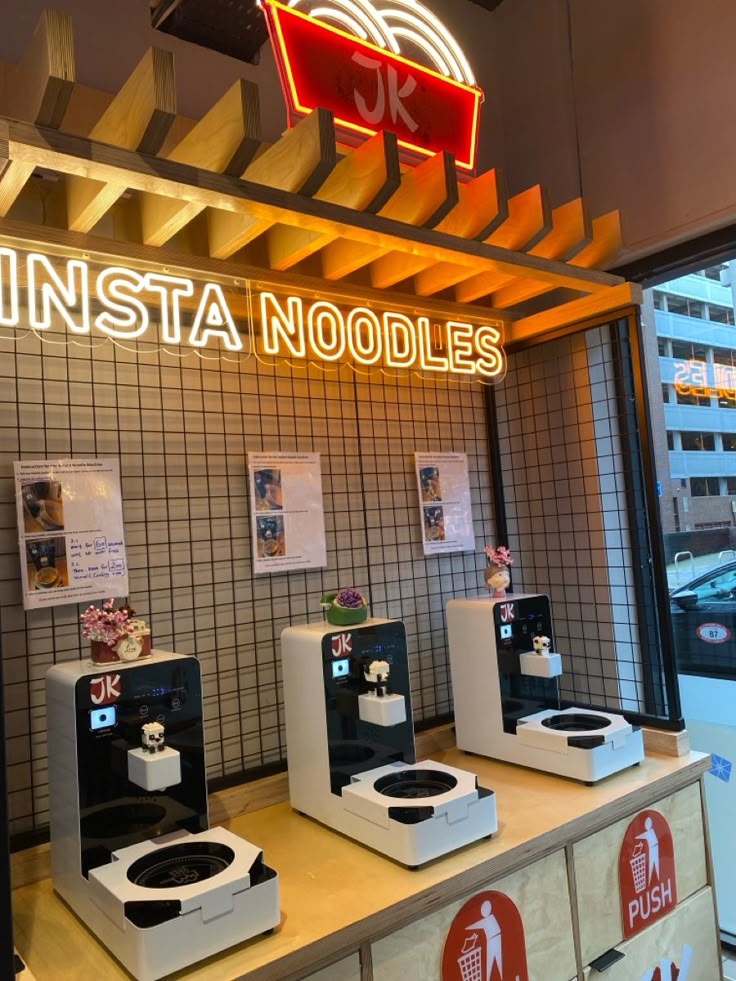 several toilets are lined up in front of a neon sign that reads insta noodles