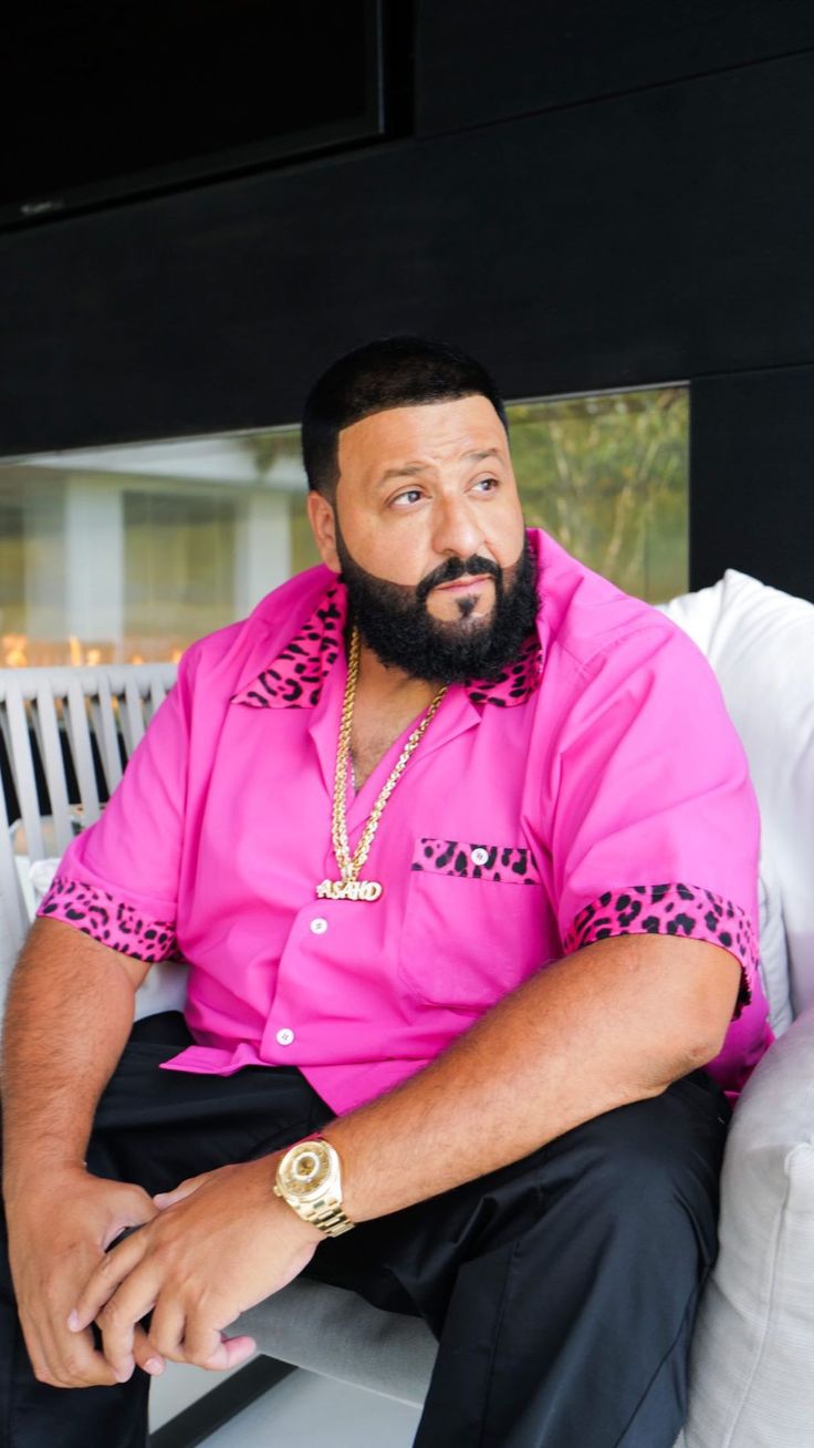 a man with a pink shirt and black pants sitting on a white couch