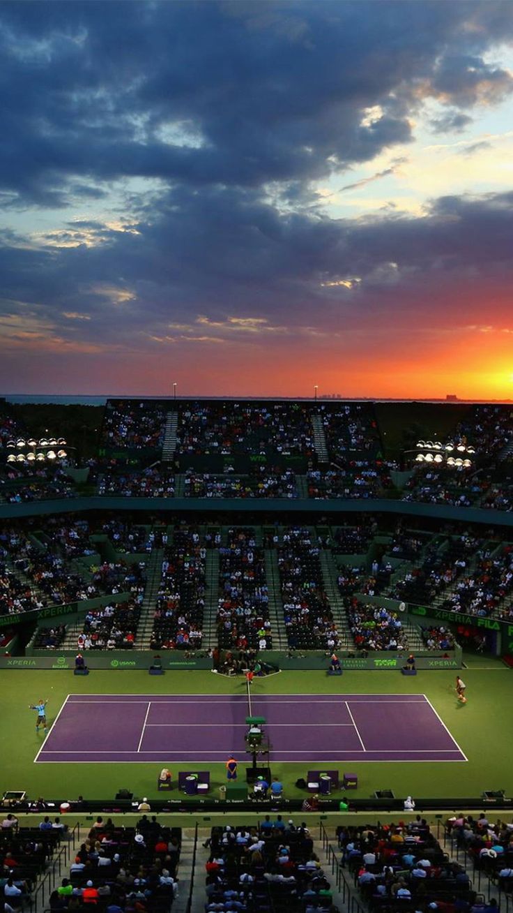 a tennis match is being played in an empty stadium at sunset with the sun going down