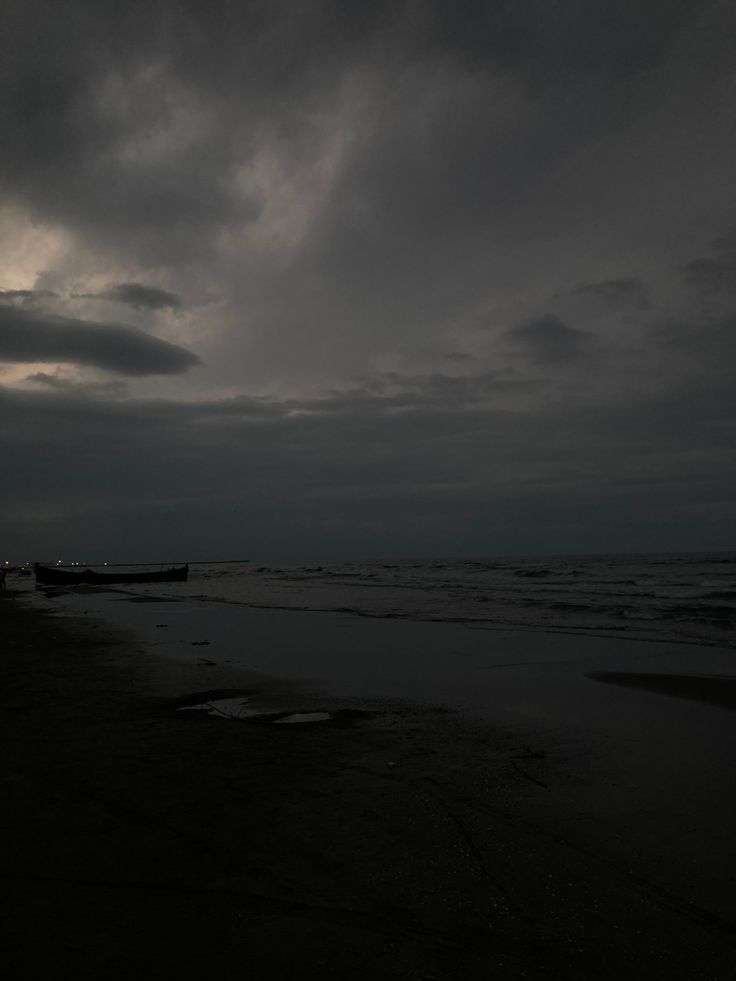 the sky is dark and cloudy at the beach