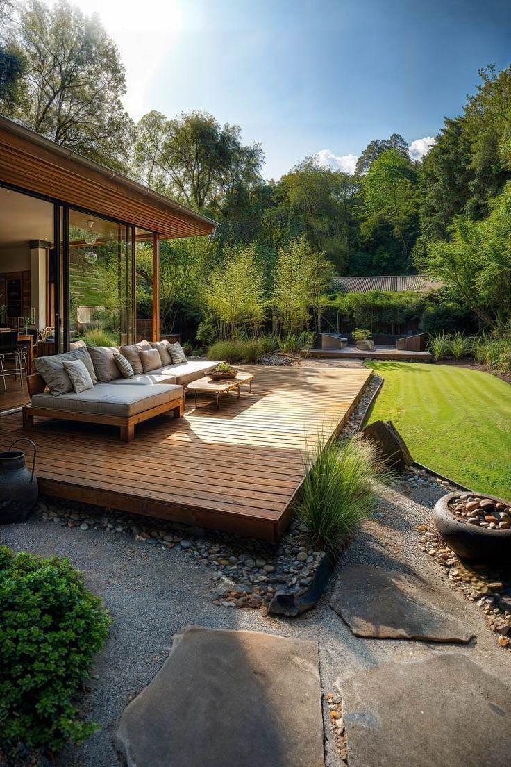 a wooden deck in the middle of a yard with couches and tables on it