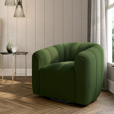 a green chair sitting on top of a hard wood floor next to a table and lamp