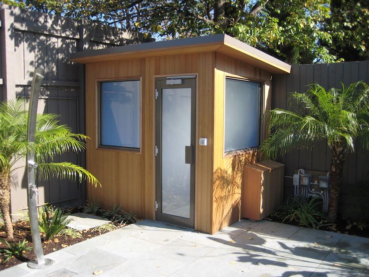 a small wooden outhouse sitting next to a palm tree