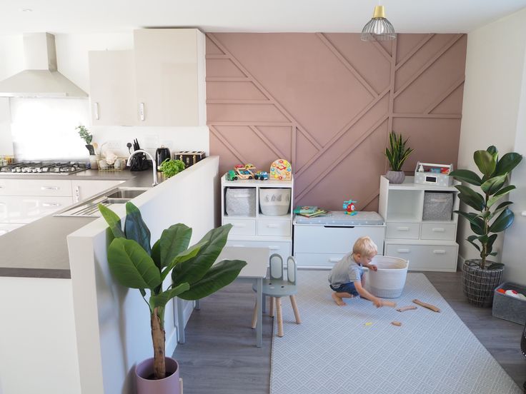 a small child playing in a play room with toys and plants on the floor next to it