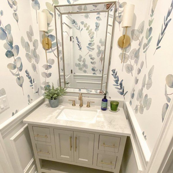 a bathroom with a sink and mirror next to a wallpapered wall behind it