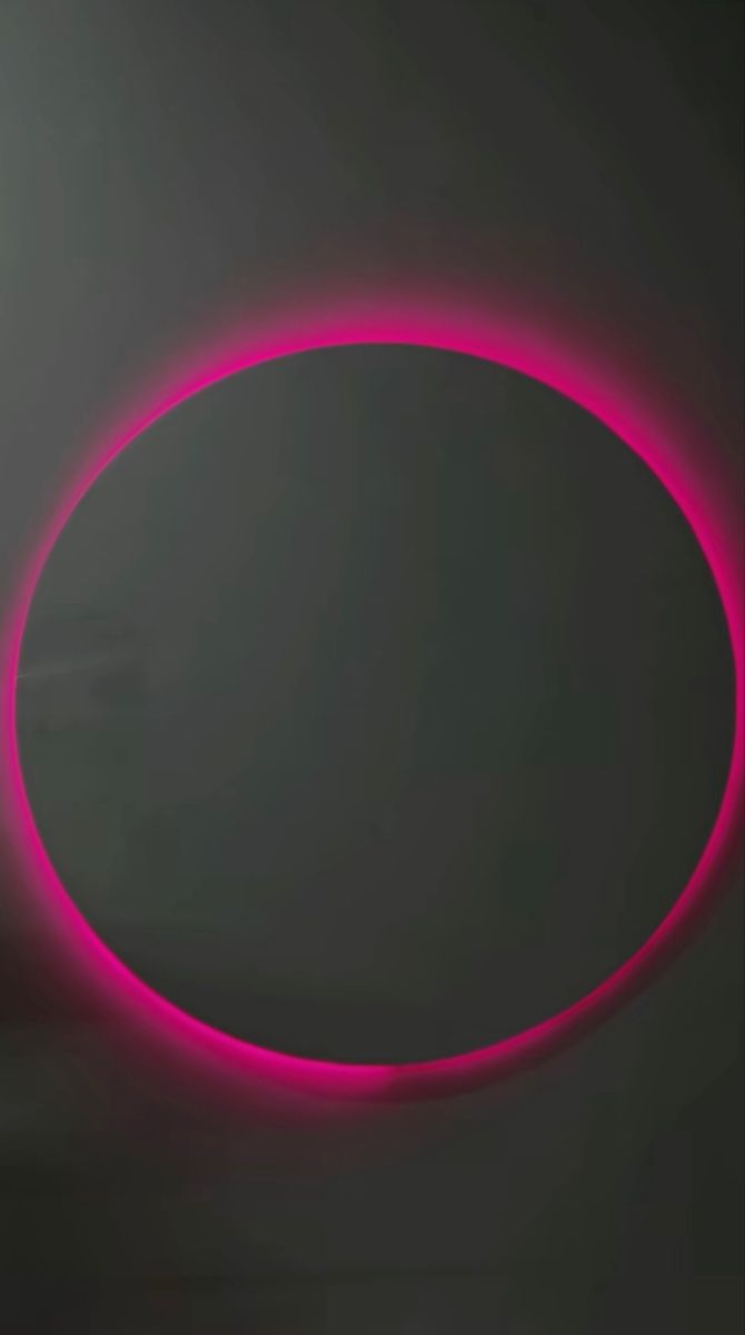 an oval shaped object is lit up in the dark with bright pink light around it