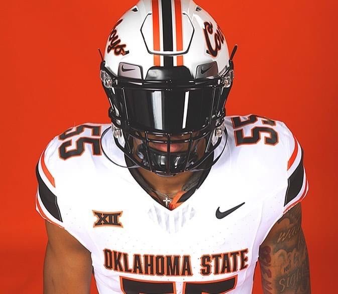 a man wearing a football uniform with tattoos on his arm and face, standing in front of an orange background