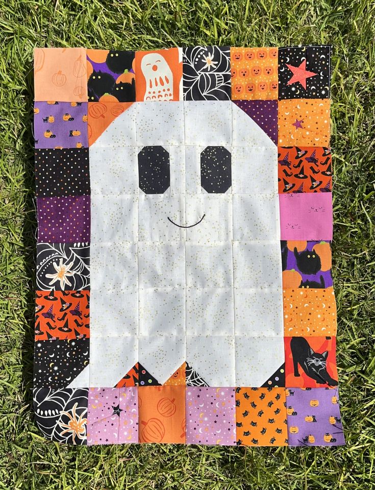 a patchwork halloween quilt with a white ghost on it's face and black eyes