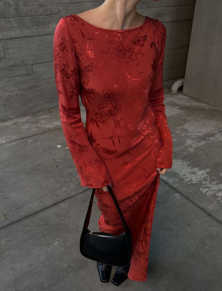 a woman in a red dress holding a black purse